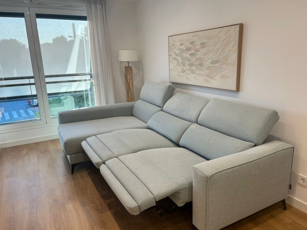 Sofá gris claro completamente limpio tras servicio de limpieza de sofás a domicilio en Pinto, mostrando resultado profesional en salón moderno y luminoso.